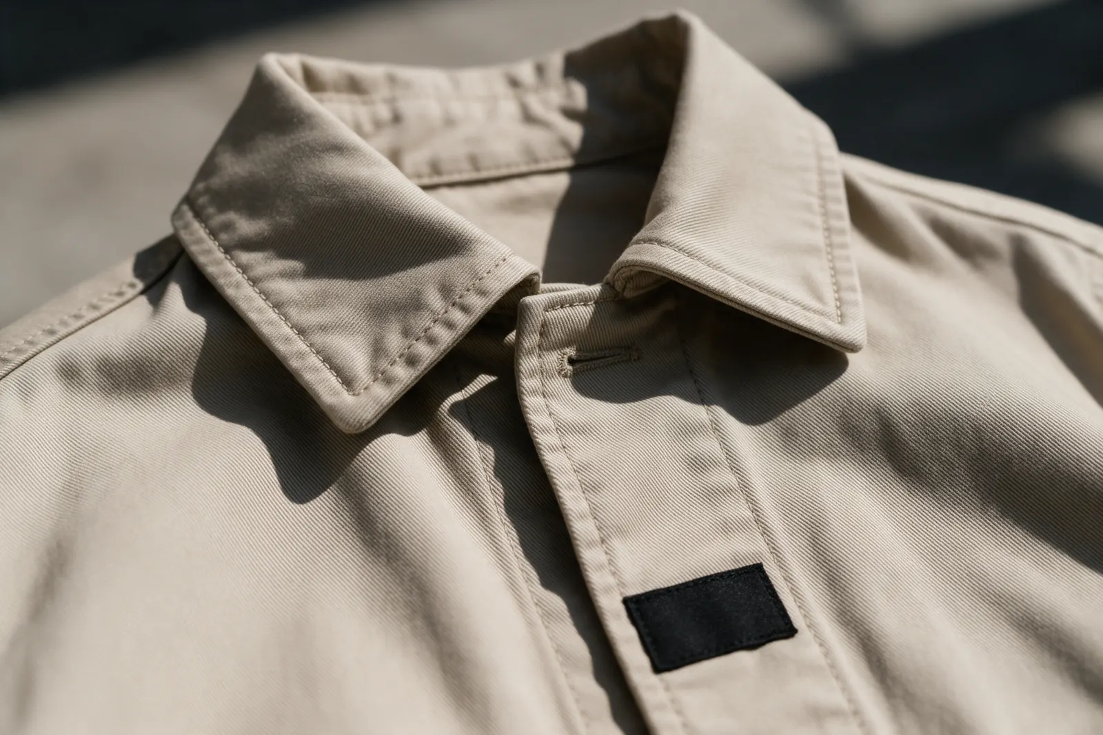 Close-up of a jacket collar with double topstitching and a small black label.
